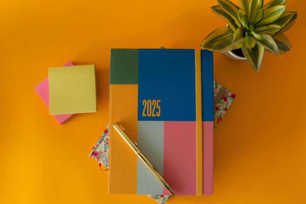 A planner with a pen on top and an orange background.