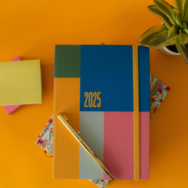 A planner with a pen on top and an orange background.