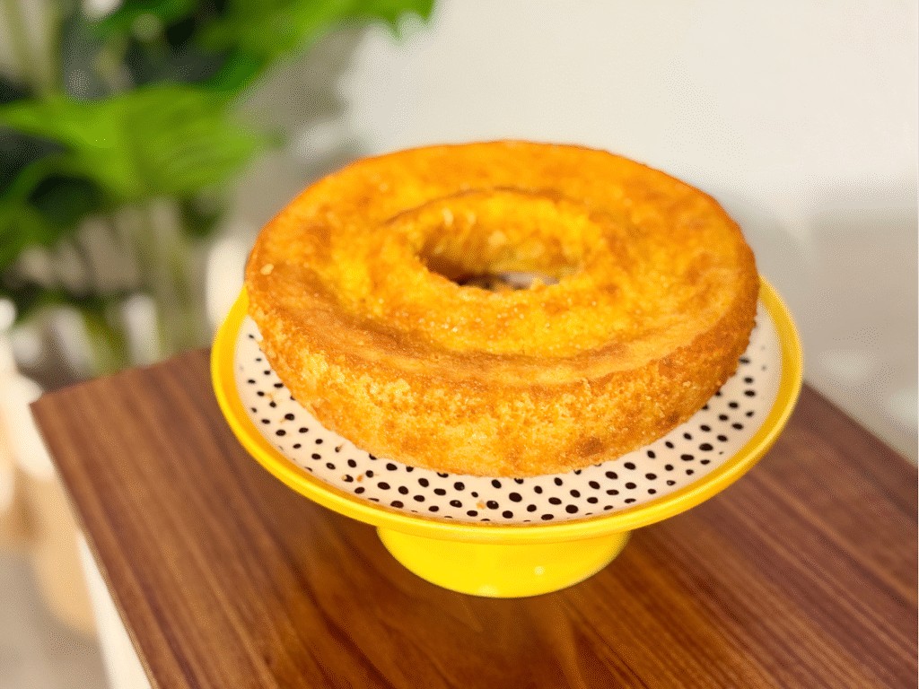 Creamy corn cake with a golden crust on a white plate, soft texture and moist center, ready to serve.