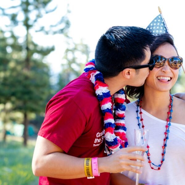 A guy kissing his girlfriend, both wearing celebration clothes.