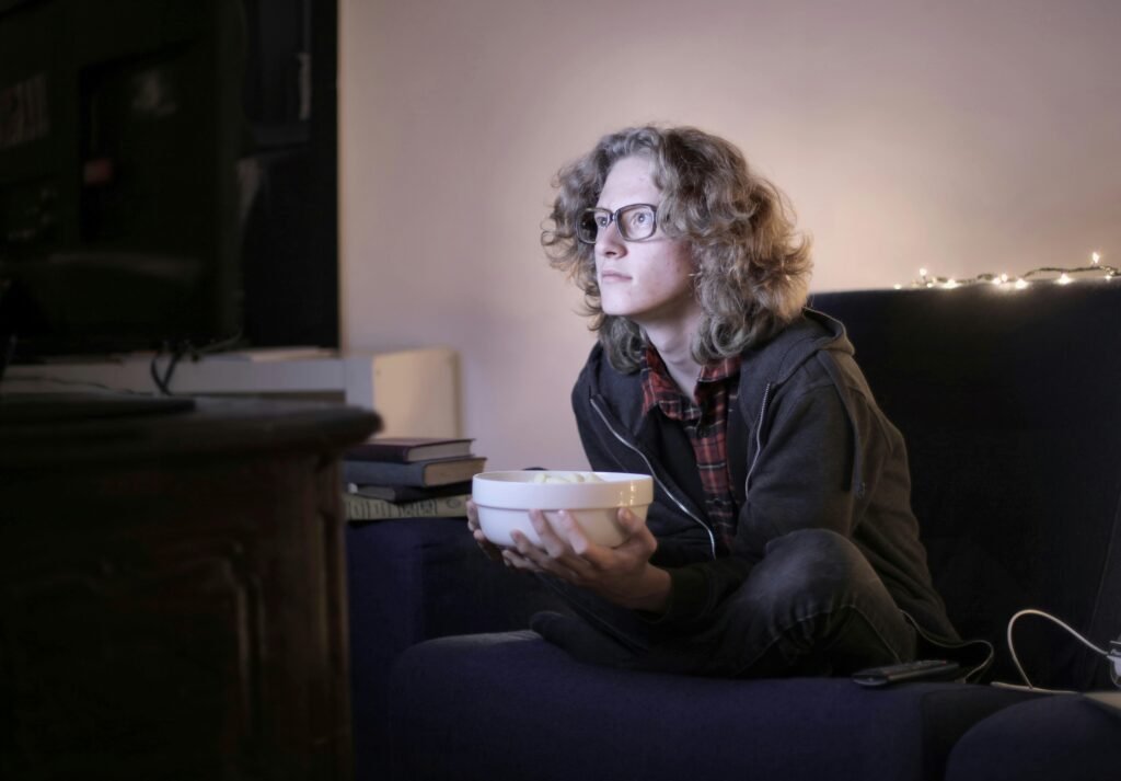 A woman watching TV with a bowl in her hand.