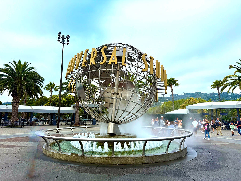 Universal globe spinning at the entrance of Universal Studios Hollywood on a sunny day.