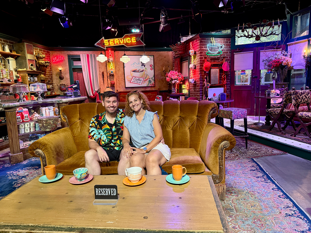 Couple sitting on the famous Friends couch inside the Central Perk set at Warner Bros Studios.
