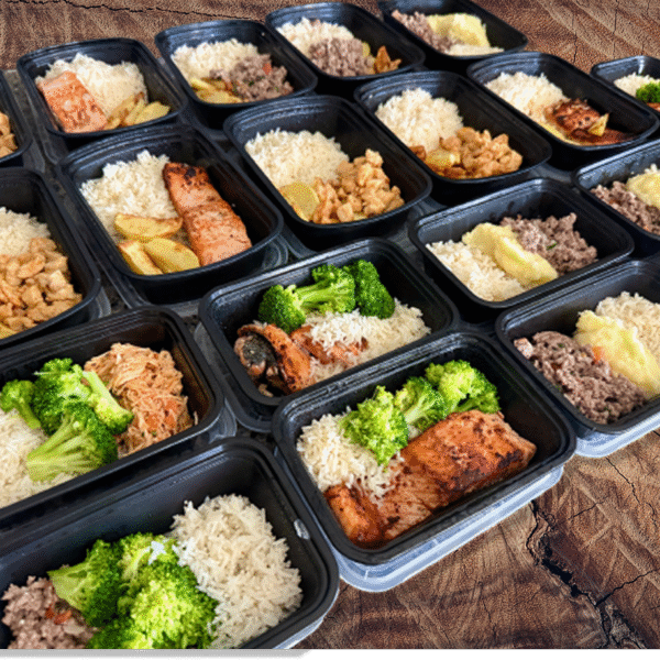 Meal prep containers with healthy family meals, including rice, vegetables, and proteins, neatly arranged on a wooden table.
