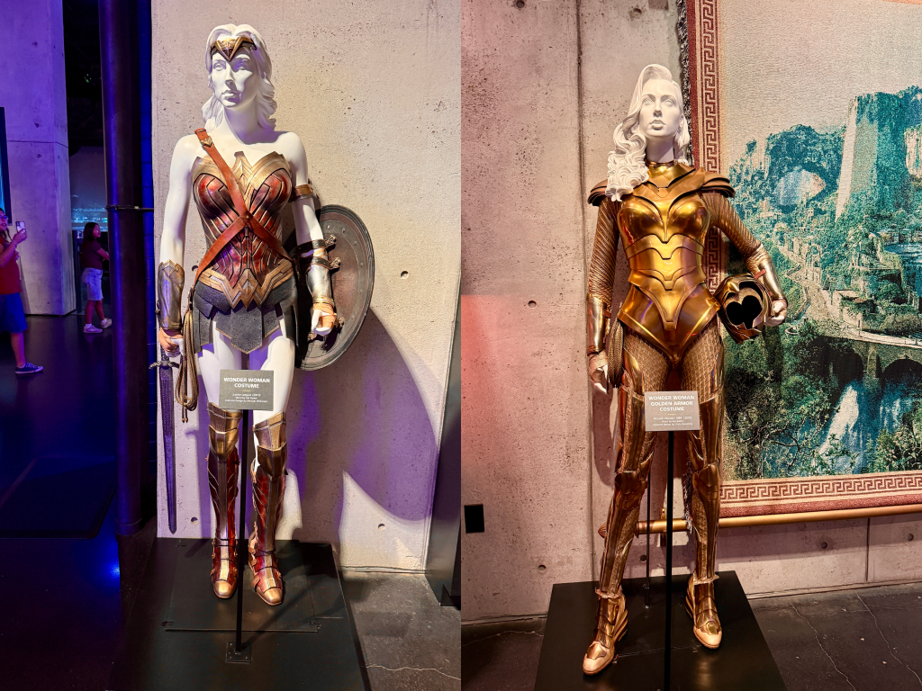 Two Wonder Woman costumes on display at Warner Bros Studios—one in the classic red, blue, and gold, and the other in full golden armor.