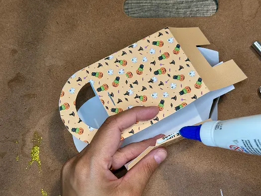 Putting glue in the side of Halloween Treat Bags.
