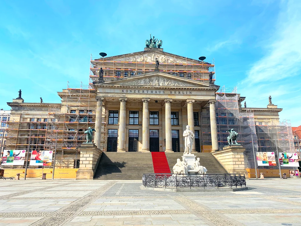 Gendarmenmarkt square in Berlin with the German Cathedral, French Cathedral, and Concert Hall illuminated at night.