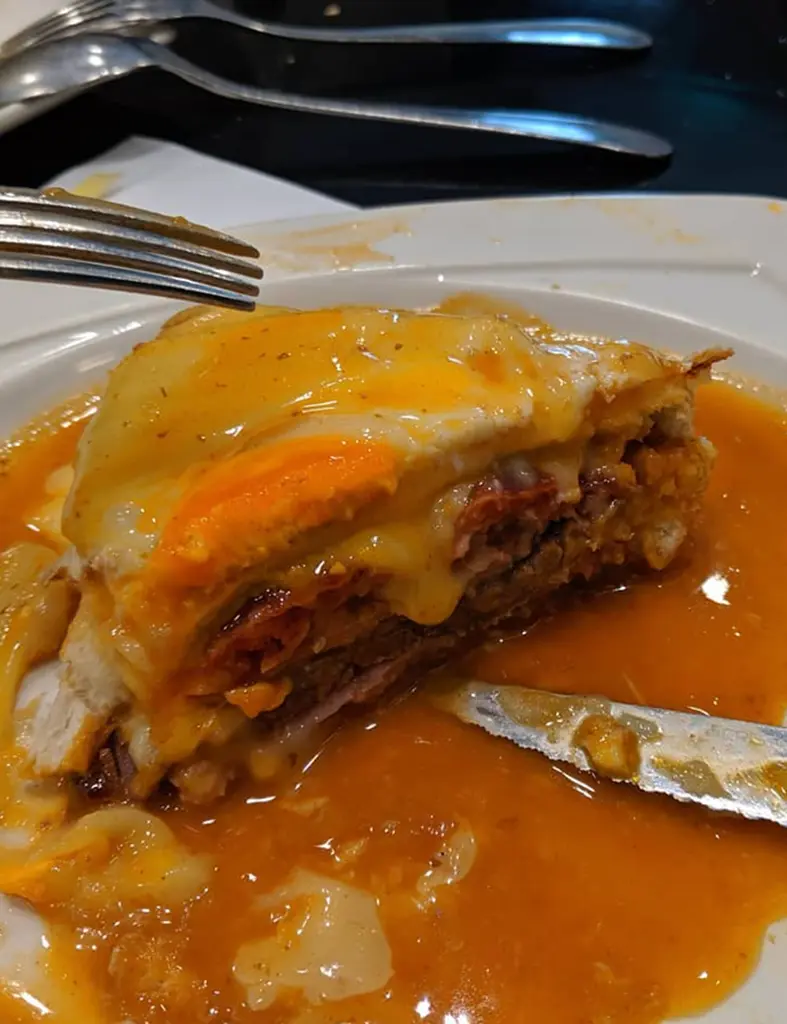 Francesinha Portuguese sandwich with melted cheese and spicy sauce