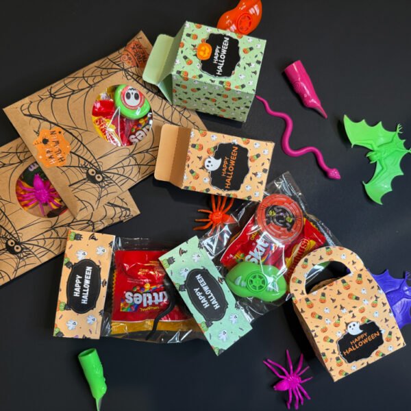 Several DIY Halloween treat bags decorated with pumpkins, ghosts, and bats, displayed on a table for kids’ party favors.