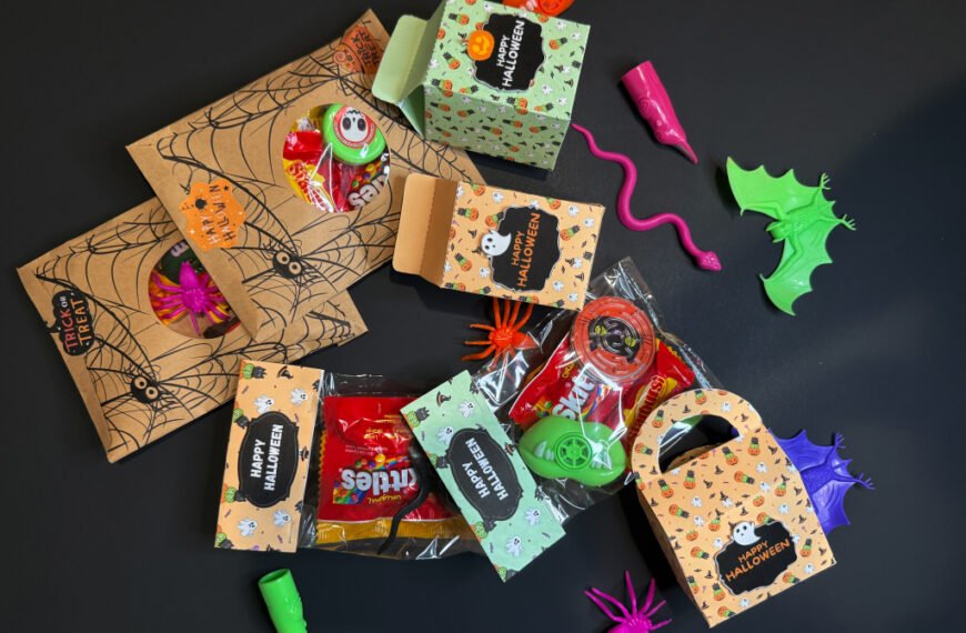 Several DIY Halloween treat bags decorated with pumpkins, ghosts, and bats, displayed on a table for kids’ party favors.