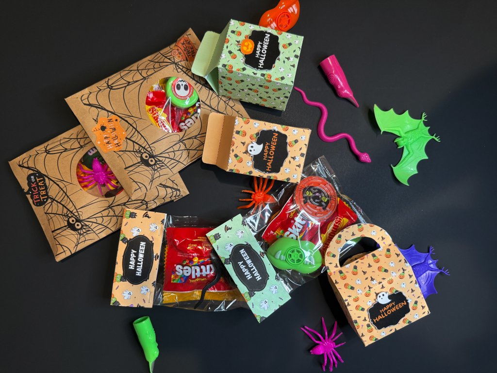 Several DIY Halloween treat bags decorated with pumpkins, ghosts, and bats, displayed on a table for kids’ party favors.