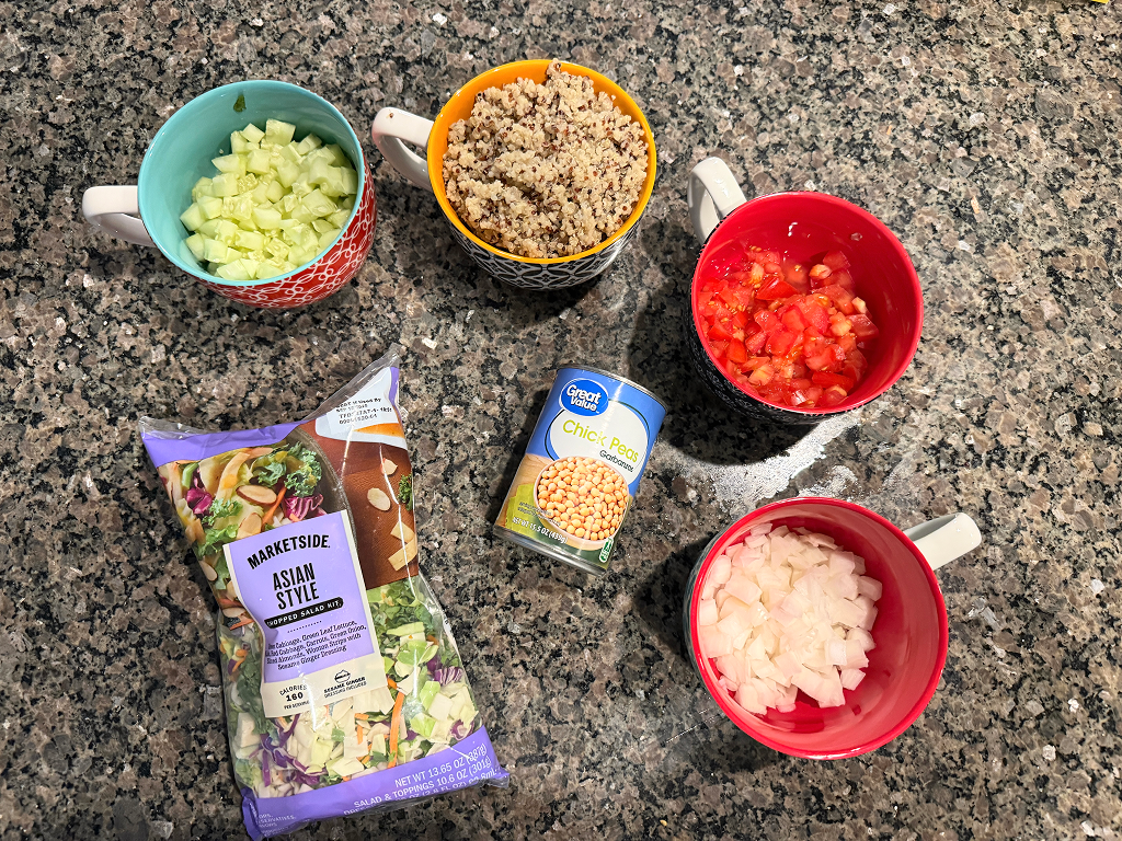 Ingredients for the protein salad, like cucumber, quinoa, lettuce, tomato, chick peas and onion.
