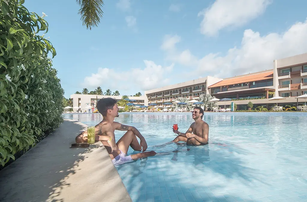 Two men enjoying drinks while relaxing in a swimming pool