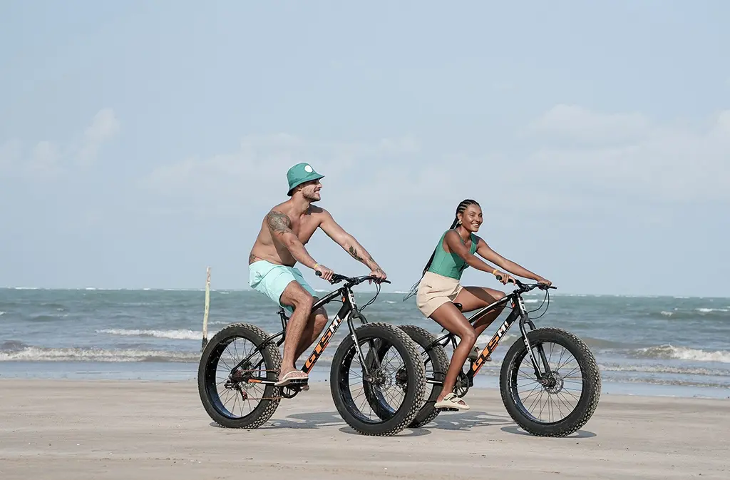 Couple riding wide-tire bikes along the beachfront area
