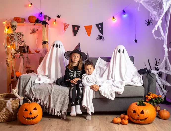 Halloween Party at home: Children posing in a Halloween photo booth with scary decorations.