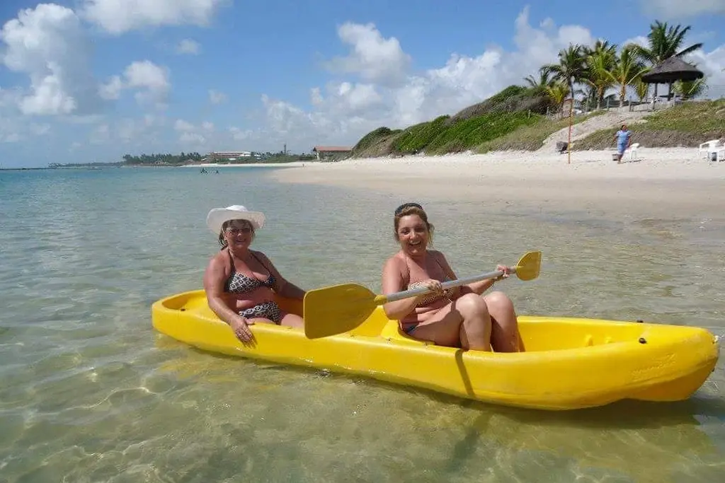 Two women kayaking in crystal-clear beach waters