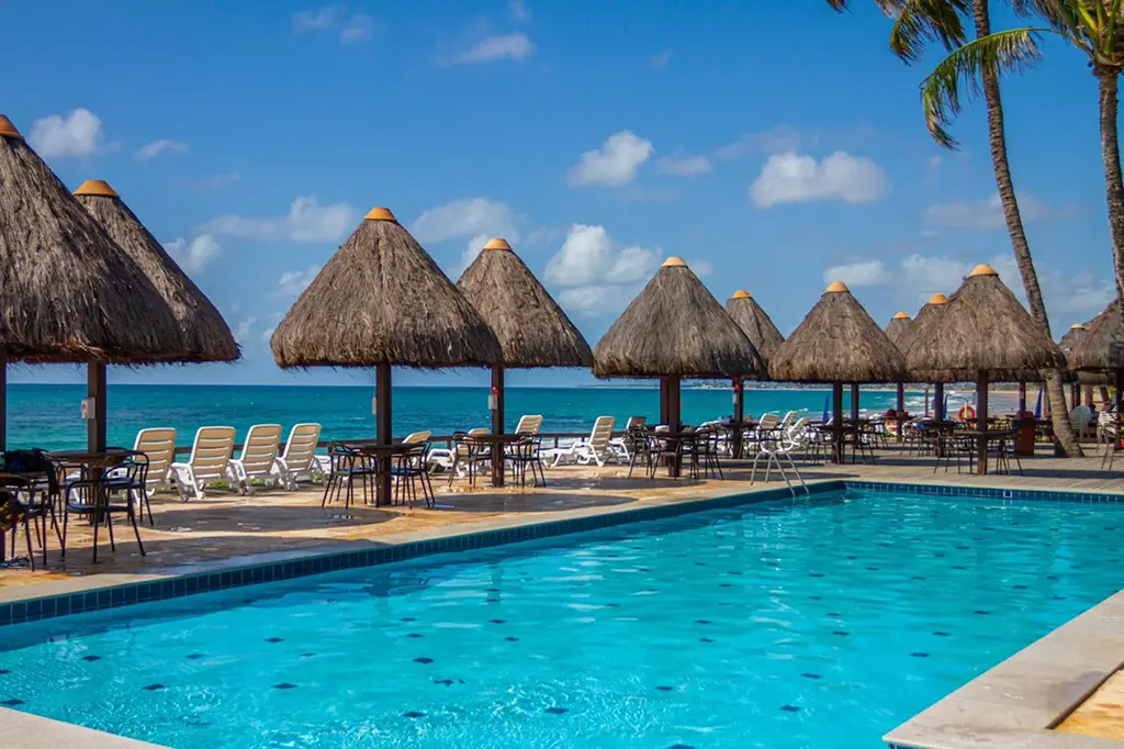 Resort swimming pool with small cabanas and sun loungers